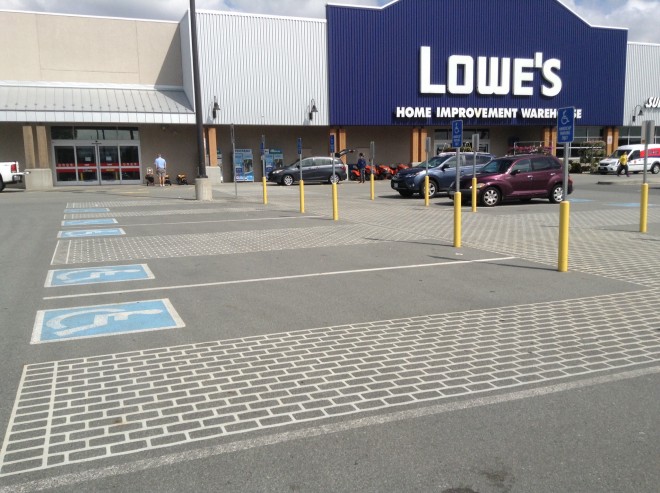 A photograph on a sunny day of three accessible parking spots in a parking lot outside of Lowe's