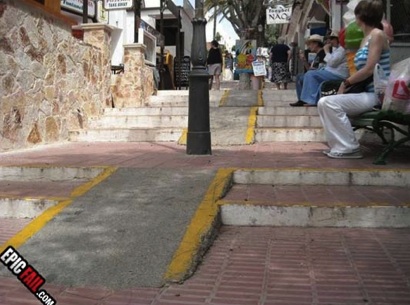 a photograph of two short ramps that go up the center of a flight of stairs. a lamppost is directly in the center of the ramp
